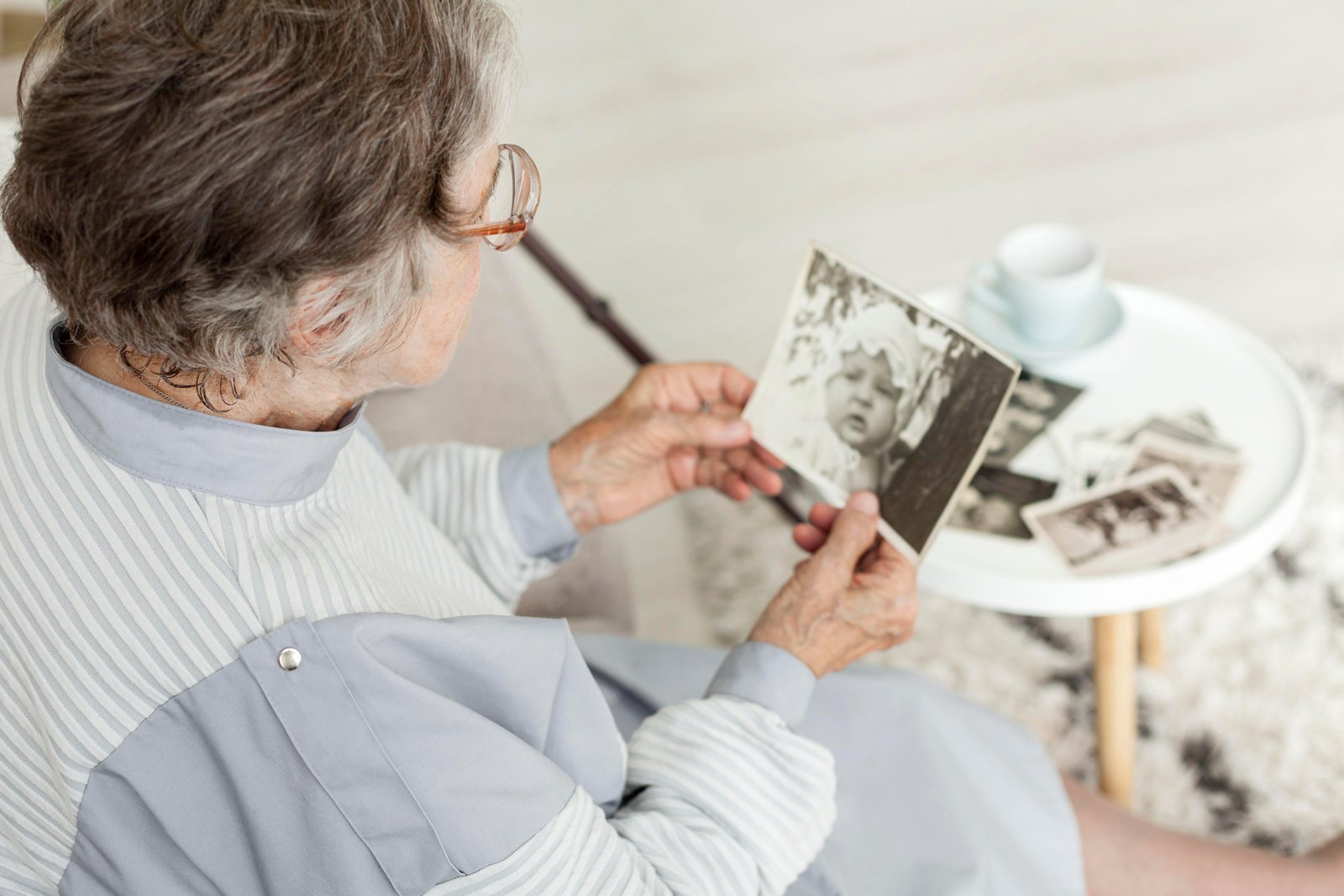 Manos de una persona mayor revisando fotografías familiares antiguas para reconstruir el árbol de herederos